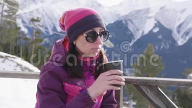 女人在<strong>山</strong>上的乡村木制露台上喝着温暖的<strong>茶</strong>。 女孩<strong>正</strong>在欣赏雪<strong>山</strong>的全景